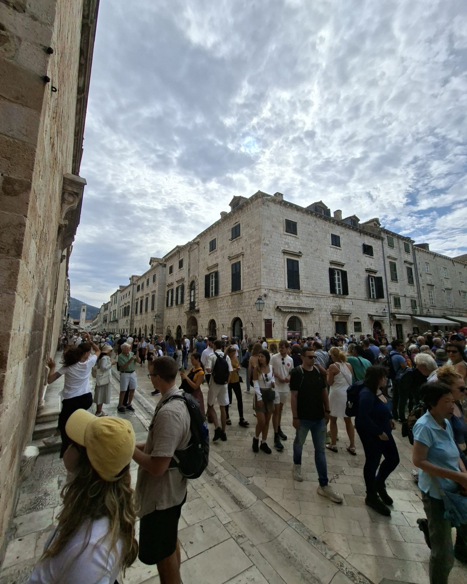 Crowded street in Dubrovnik Old Town with large groups of visitors.