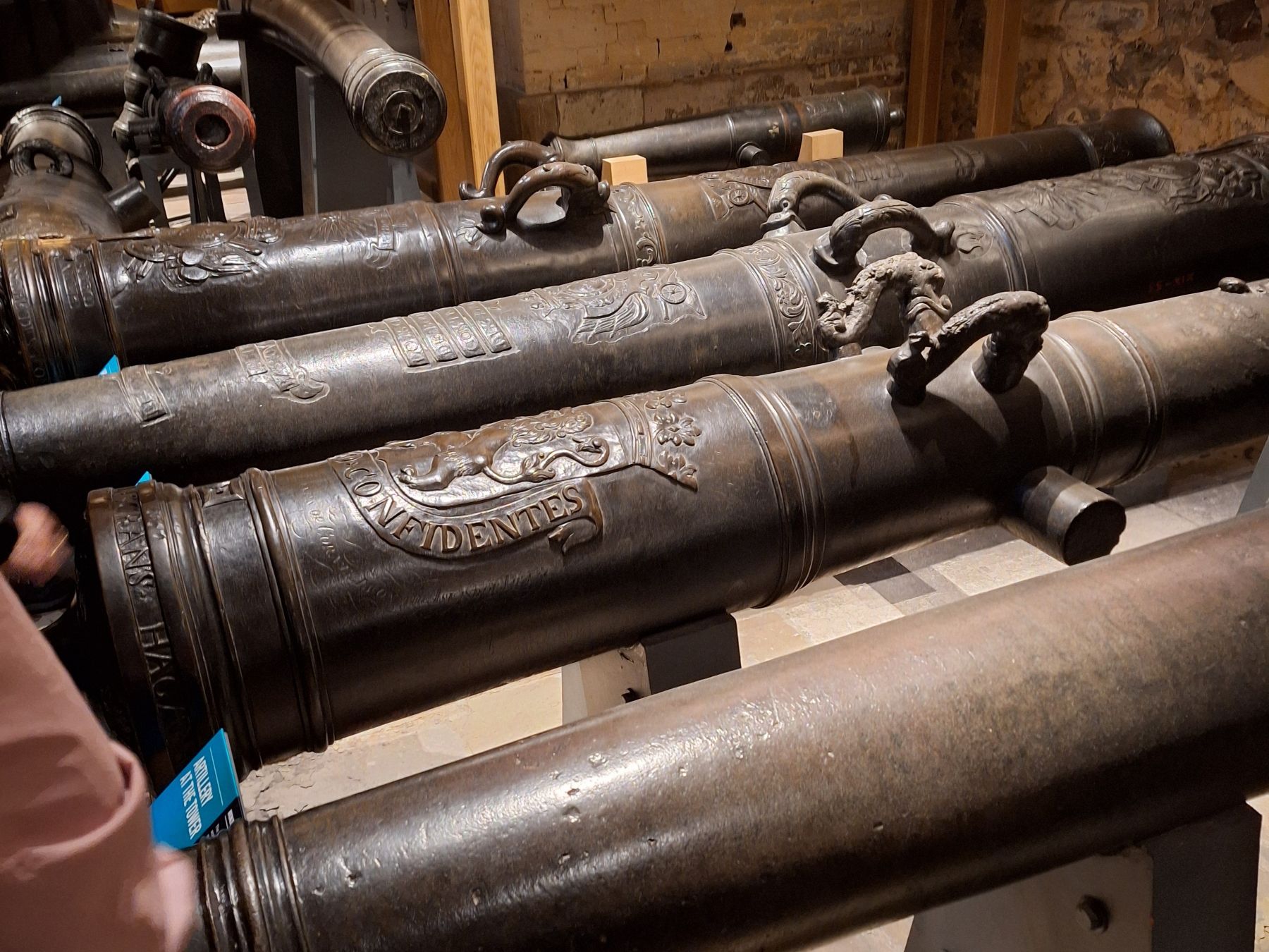 Historic cannons and armour displayed inside the Tower of London, arranged in rows on wooden supports